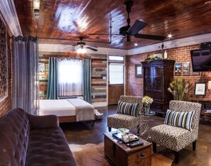 A cozy room with a bed, two patterned armchairs, a sofa, a wooden coffee table, and a ceiling fan. - Side-By-Side Both Places, Groups Can Spend More Time Together! (New Iberia)