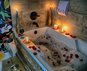 A bathtub filled with water and rose petals, surrounded by candles and bottles of wine. - Side-By-Side Both Places, Groups Can Spend More Time Together! (New Iberia)
