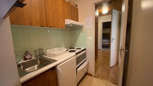 Una cocina compacta con armarios de madera, una estufa blanca y un lavamanos.