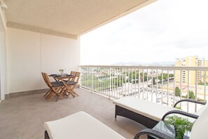 Un balcón con una mesa de comedor y sillas, un sofá y una planta en maceta.