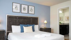 A neatly made bed with white linens, a dark wooden headboard, and blue and white pillows. There are three framed floral artworks on the wall above the bed. - Beautiful 5-Bedroom Home with Pool (Four Corners)