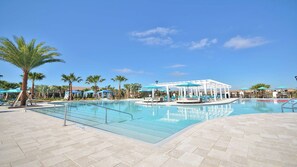A pool area with palm trees, lounge chairs, and umbrellas.