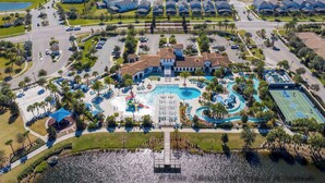An aerial view of a residential area with a large house featuring a swimming pool, tennis court, and landscaped gardens. - Beautiful 5-Bedroom Home with Pool (Four Corners)