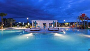 A swimming pool with a central seating area and a children's play structure. - Beautiful 5-Bedroom Home with Pool (Four Corners)