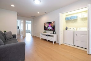 A modern living room with a flat-screen TV, a grey sofa, and a white entertainment unit.