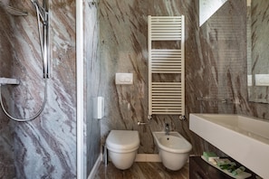 A bathroom with a marble wall, a shower, a toilet, a bidet, and a sink. - 3111 Villa Carra by Perle di Puglia (Parabita)