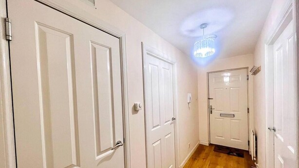 A hallway with white doors, a wooden floor, and a ceiling light fixture. - Lovely 2-bed Apartment in Aberdeen (Aberdeen)