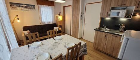 Cozy dining area with table for four, adjacent to a compact kitchenette and comfortable living space.