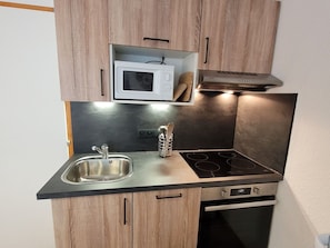 A compact kitchen with a microwave, stove, and sink.