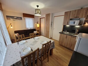 A compact kitchen with wooden cabinets, a microwave, and a dining area with a table set for four.