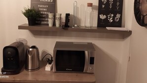 En köksbänk med en mikrovågsugn, en kaffebryggare, en vattenkokare och en liten krukväxt.