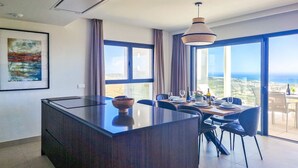 Une cuisine moderne dotée d’un îlot central, de grandes fenêtres et offrant une vue sur la mer.