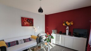A modern living room with a sofa, coffee table, and a red accent wall. - Charming apartment with terrace and garden, perfect for 4 people, in Barbezieux (Barbezieux-Saint-Hilaire)