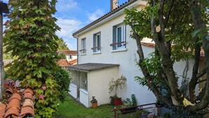 A two-story house with a white facade, a tiled roof, and a small garden area with a fence. - Charming apartment with terrace and garden, perfect for 4 people, in Barbezieux (Barbezieux-Saint-Hilaire)