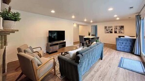 A modern living room with a TV, sofa, chairs, and a dining area. - Serene Mercer Island 3B Lower Unit near LR station (Mercer Island)