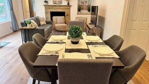A dining area with a table set for four, surrounded by chairs, a fireplace, and a sofa. - Serene Mercer Island 3B Lower Unit near LR station (Mercer Island)