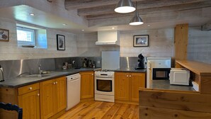 A kitchen with wooden cabinets, a dishwasher, a stove, a microwave, and a sink. - Cozy Countryside Cottage with Spacious Garden – Sleeps 4-5 (Douchy-Montcorbon-Douchy)