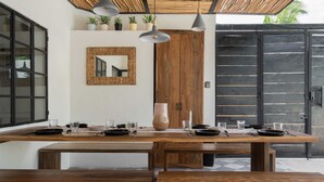 A dining area with a wooden table set for four, a large mirror, and potted plants on the wall. - Amazing Villa in la Veleta 14 pax (Tulum)