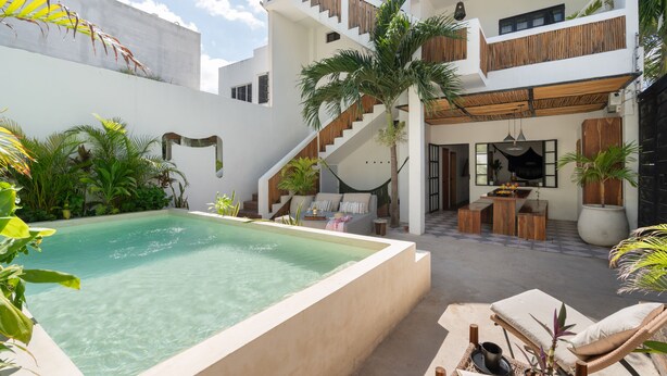A modern outdoor pool area with a staircase leading to a balcony, surrounded by lush greenery and a cozy seating area. - Amazing Villa in la Veleta 14 pax (Tulum)