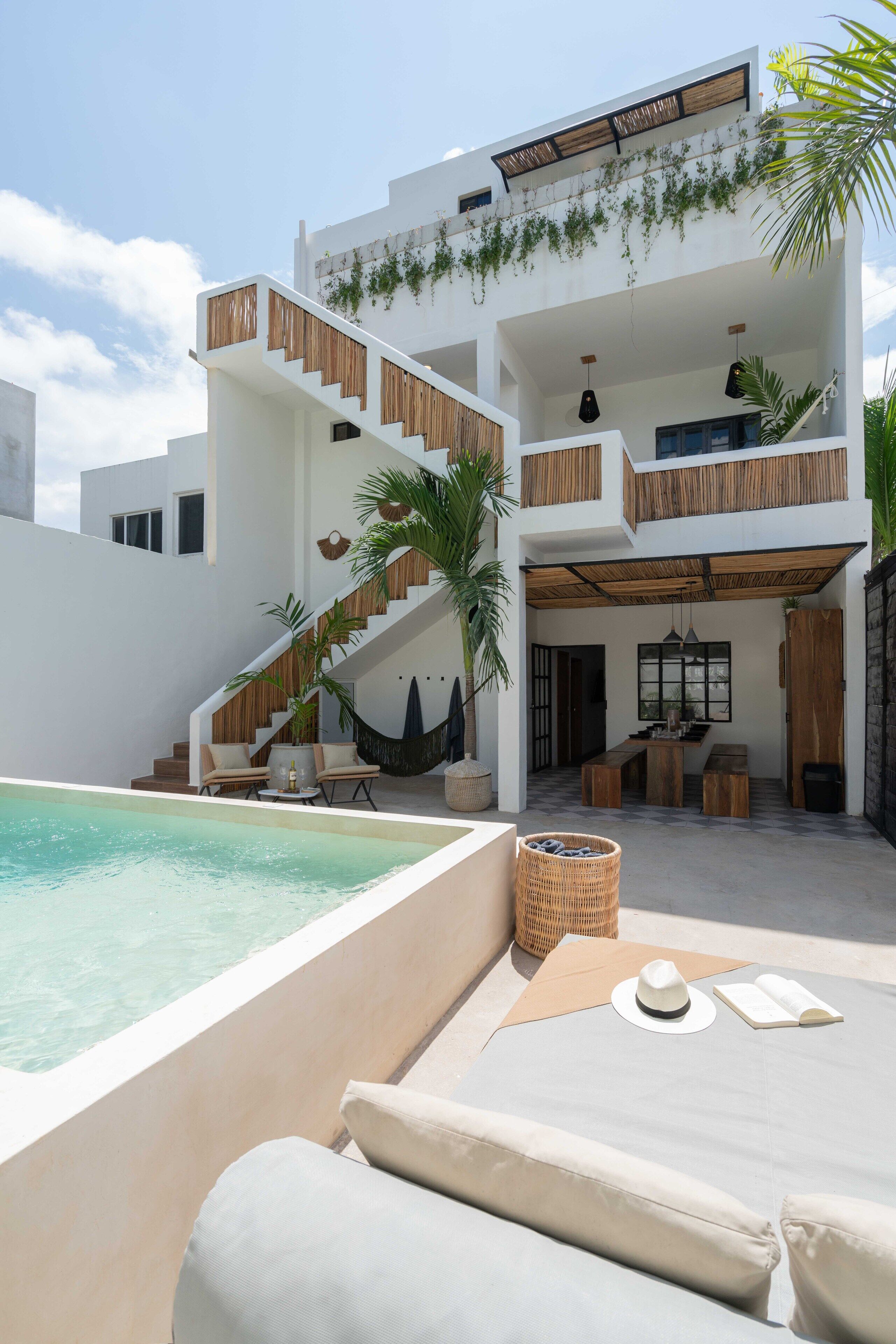 A modern multi-level house with a pool, outdoor seating, and a staircase.