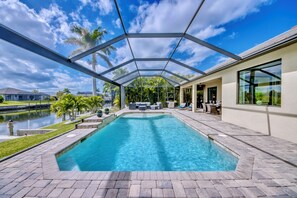 A covered swimming pool with a patio area, a view of the water, and a building with large windows. - Villa Sweet Mailin - on water, pool, foosball, contemporary design (Cape Coral)