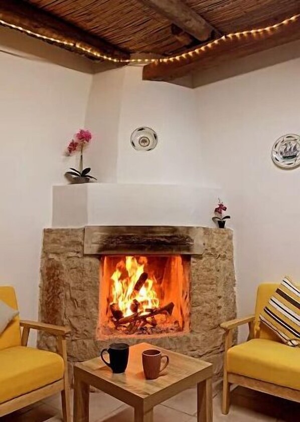A cozy room with a stone fireplace, wooden furniture, and a ceiling with exposed beams. - Studio with amazing mountain view  (Στρουμπί)