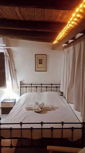 A single bed with a metal frame, a bedside table, and a wall-mounted picture.