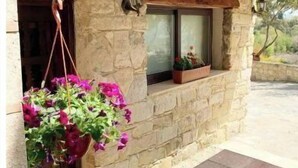 Un edificio de piedra con techo de madera, una maceta colgante y una ventana.
