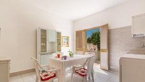 A compact kitchen with a dining table, chairs, and a cabinet. - 3052 A Casa di Mario - Appartamento Sabbia by Barbarhouse (Porto Cesareo)