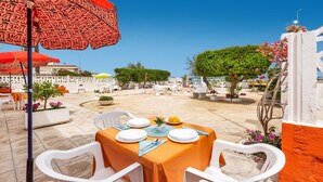An outdoor dining area with a table set for two, surrounded by white chairs, under a red umbrella with 'LOVE' written on it. - 3052 A Casa di Mario - Appartamento Sabbia by Barbarhouse (Porto Cesareo)