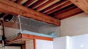 Een compacte keuken met een eethoek, houten balken in het plafond en betegelde vloer.