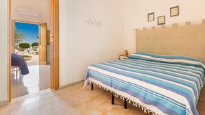 Ein Schlafzimmer mit einem Bett, einem Nachttisch und Blick ins Freie.