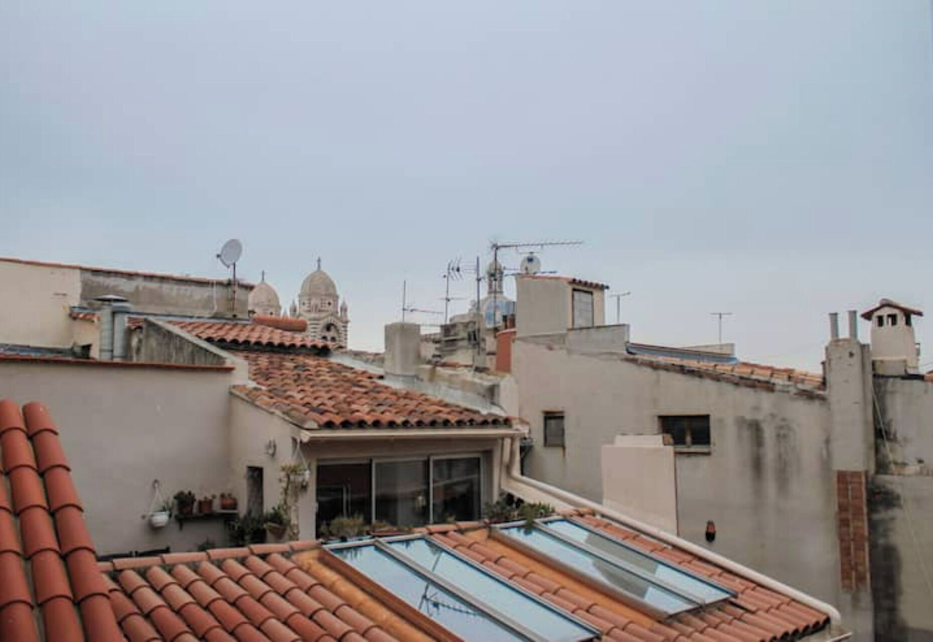 A rooftop with a swimming pool, terracotta tiles, and a view of nearby buildings including a dome structure.