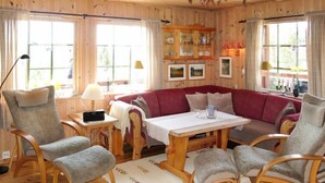 Ein gemütliches Zimmer mit Holzwänden und Holzdielen, einem roten Sofa und einem Holztisch mit Stühlen.