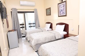 A hotel room with two beds, a small refrigerator, and a window with curtains. - DEIRA PALACE HOTEL (Dubai)