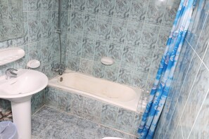 A bathroom with a sink, bathtub, and shower curtain. - DEIRA PALACE HOTEL (Dubai)