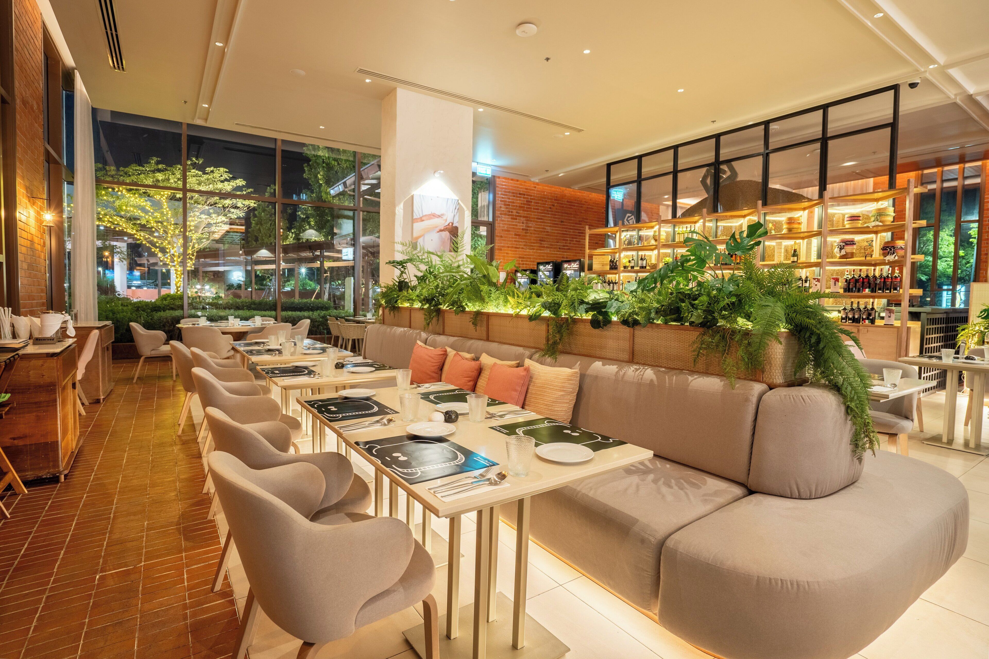 Un restaurante moderno con un amplio comedor, asientos acolchados y una barra con estantes llenos de botellas.