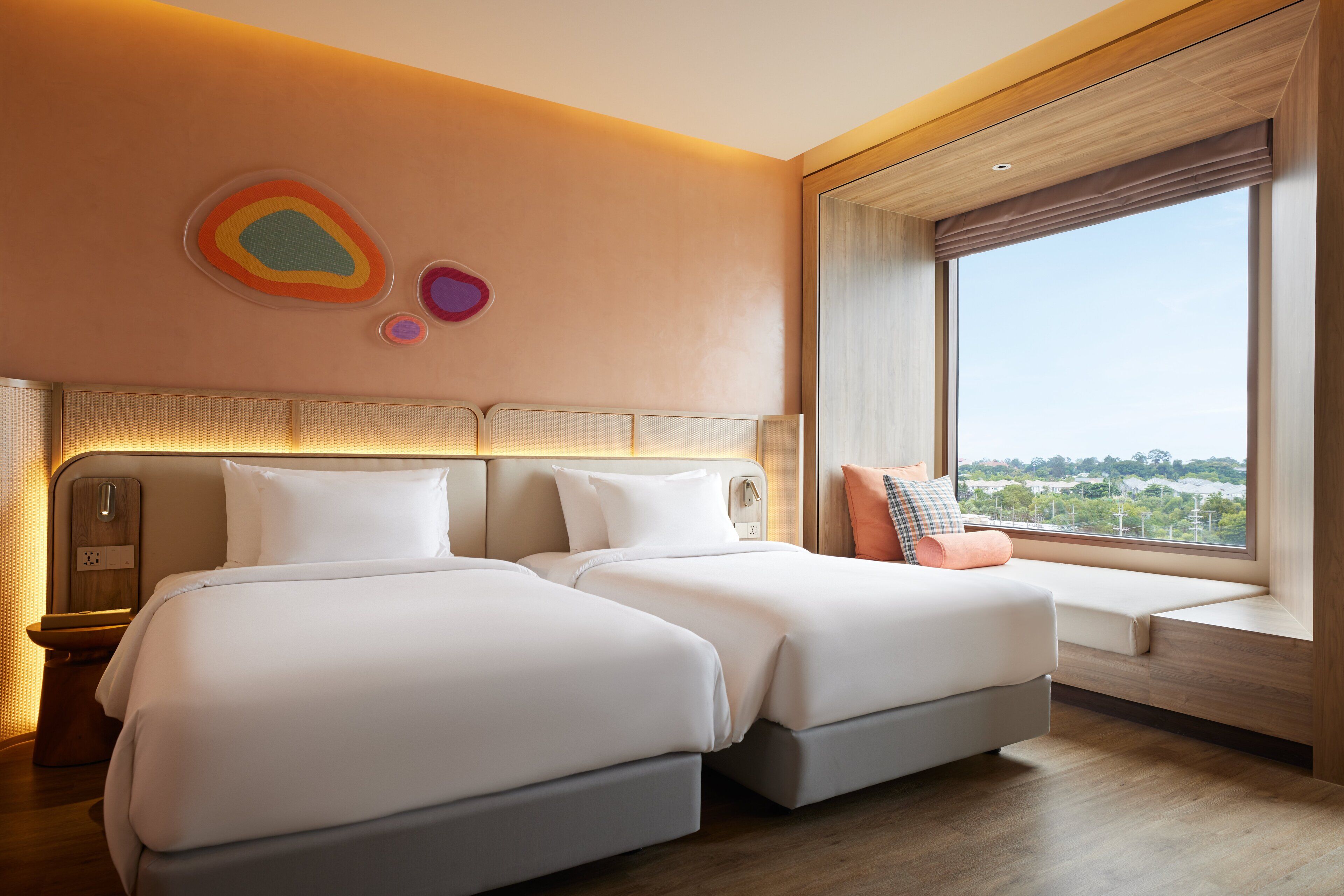 Una habitación de hotel con dos camas, un ventanal grande y vista a la ciudad.
