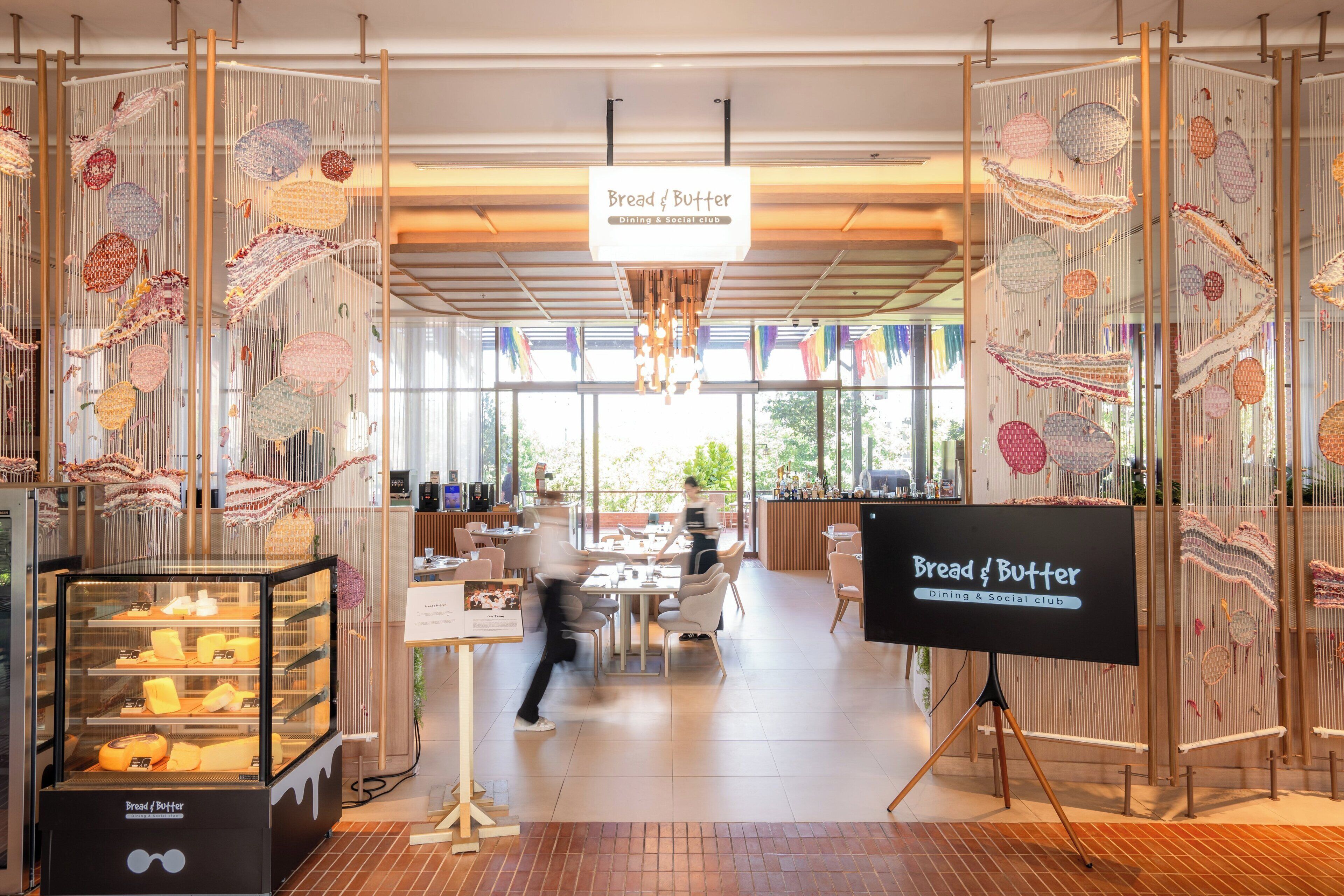 A modern dining area with a central table, a display case with bread and butter, and a sign indicating it's a dining and social club.