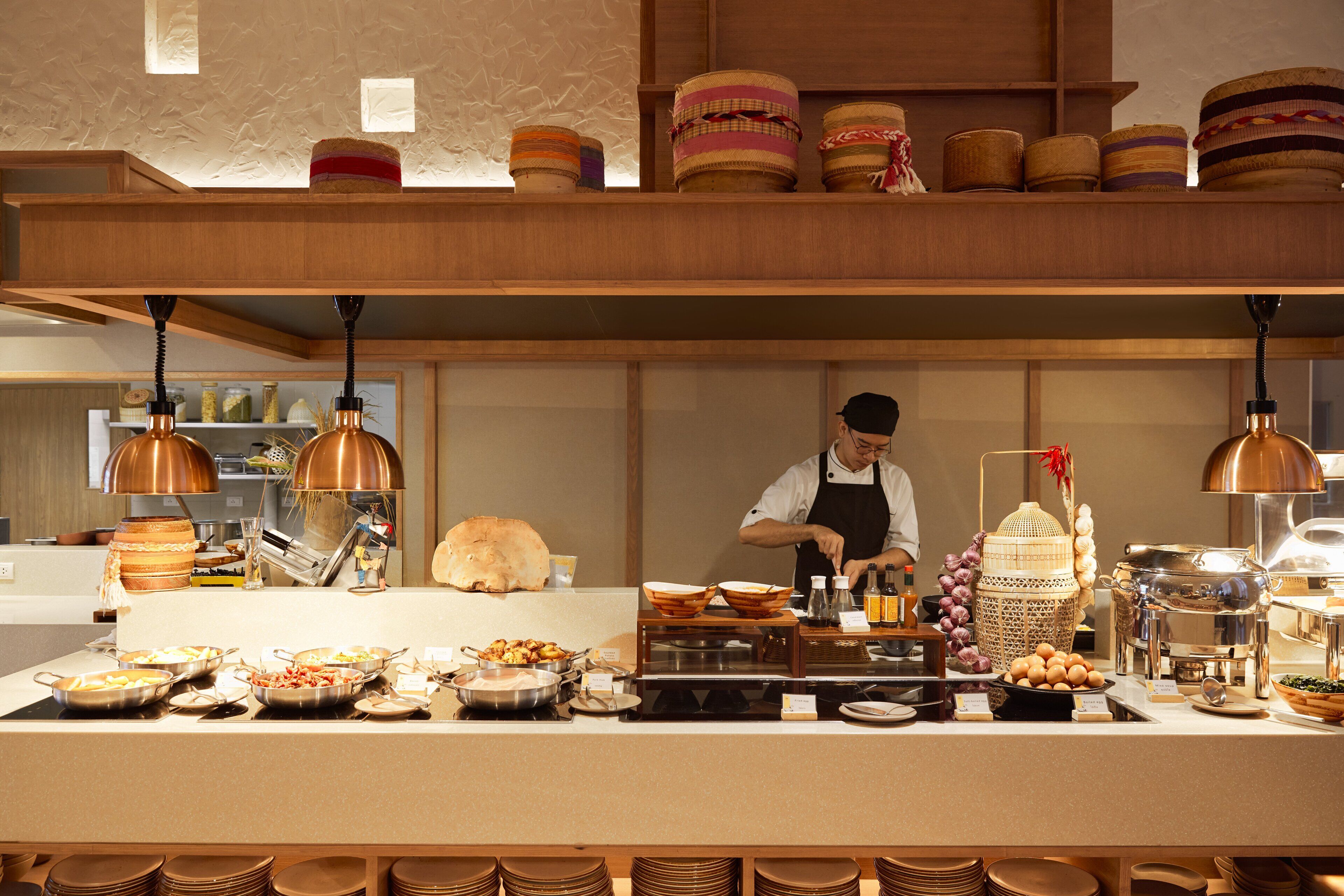 A buffet setup with various food items and a chef preparing food.