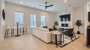 A spacious living room with a white sofa, two black chairs, a coffee table, and a ceiling fan. - 4 - Music Row Modern - The Music City Collection (Nashville)