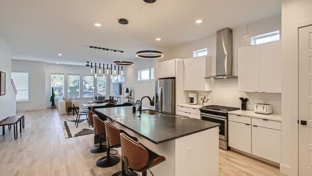 A modern kitchen with a central island, white cabinetry, and a large window providing natural light. - 5 - Music Row Modern - The Music City Collection (Nashville)