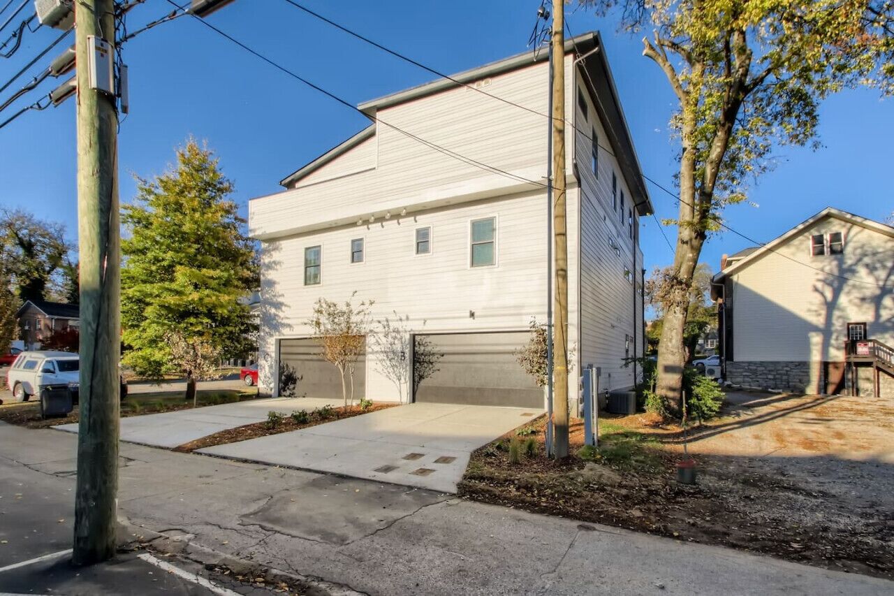 A two-story house with a garage, surrounded by trees and a driveway.
