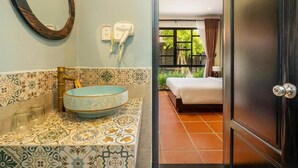 A bathroom with a patterned tile backsplash, a blue ceramic sink, and a mirror. - Sunshine Villa Hoi An (Da Nang)