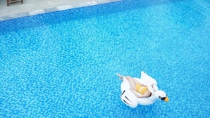 A person floating on a duck-shaped inflatable in a clear blue pool. - Sunshine Villa Hoi An (Da Nang)