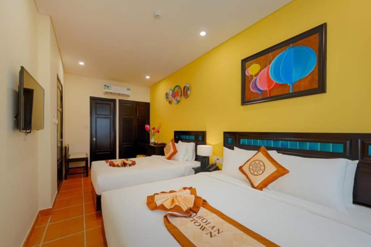 A hotel room with two beds, a TV, and a painting on the wall.