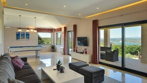 A modern living room with a pool table, comfortable seating, a flat-screen TV, and a balcony with a scenic view. - Villa Rachele (Istria - Rakalj) (Rakalj)