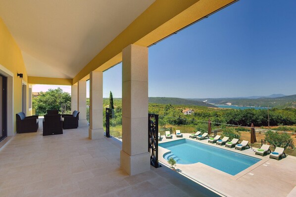 A balcony with a pool, outdoor seating, and a view of the landscape. - Villa Rachele (Istria - Rakalj) (Rakalj)