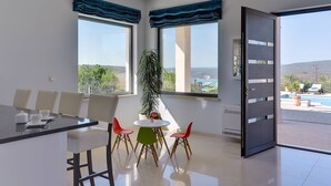 A modern dining area with a round table, four chairs, and a bar counter. - Villa Rachele (Istria - Rakalj) (Rakalj)
