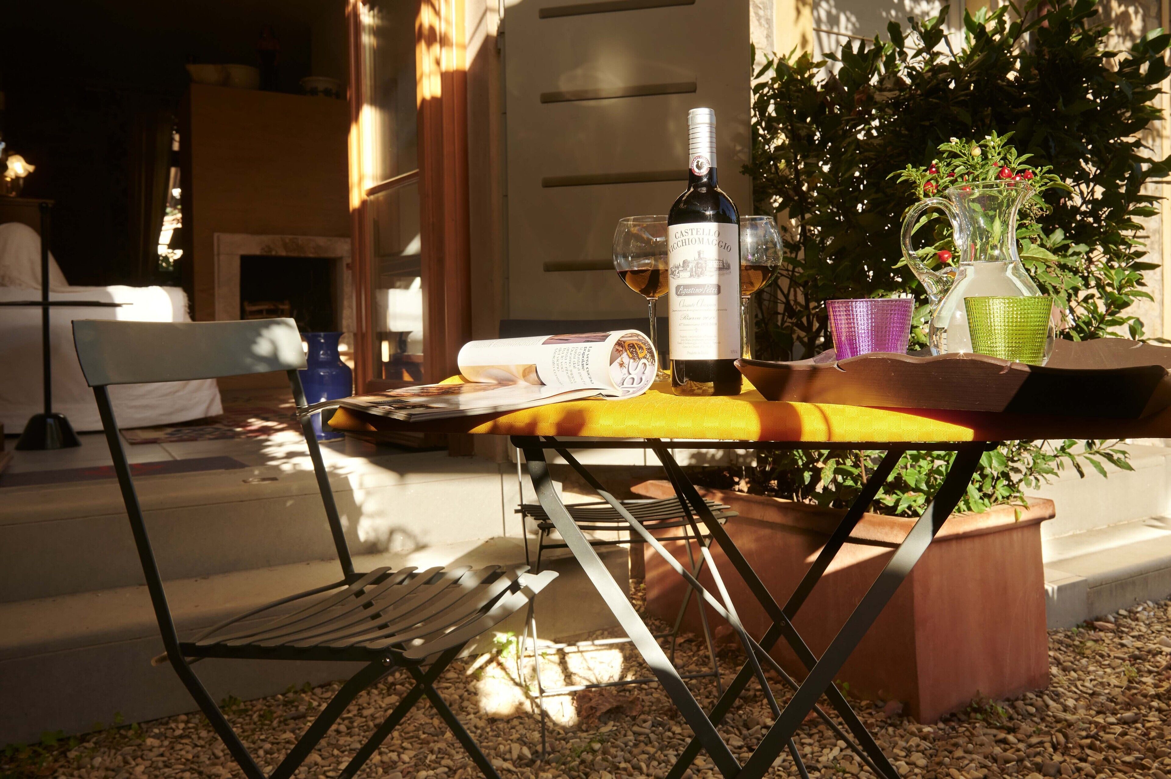 An outdoor dining area with a table set for two, a bottle of wine, and a pitcher of water.